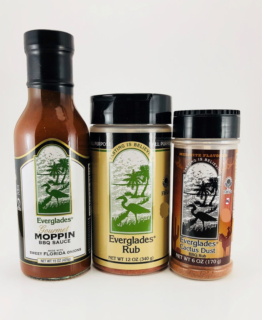 Three bottles of Everglades brand BBQ products, including a mop sauce, rub, and jerk marinade, arranged side by side.